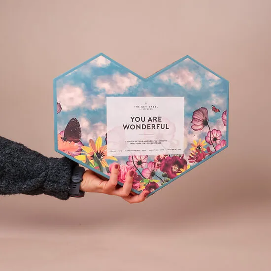 Hand holding the floral heart-shaped wellness gift box