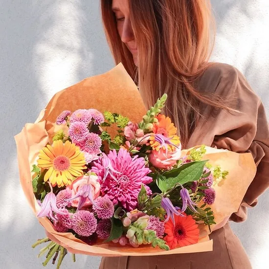 Woman holding the Poésie de saison bouquet wrapped in kraft paper